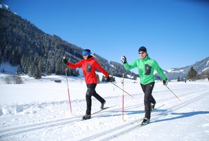 Zwei Personen beim Langlaufen in verschneiter Landschaft