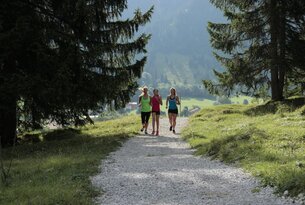 Drei Frauen joggen auf einem Kiesweg in den Bergen