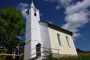 Kleine weiße Kirche mit Turm unter blauem Himmel