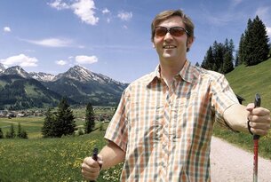 Mann mit Sonnenbrille und Wanderstock in Berglandschaft