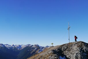 Bergspitze mit Gipfelkreuz unter blauem Himmel