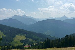 Berglandschaft mit bewaldeten Hügeln und blauem Himmel