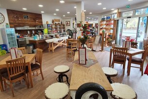 Innenansicht eines hellen Cafés mit Holztischen und Stühlen