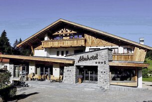Almhotel mit Holzfassade, Balkon und Steinverkleidung am Eingang