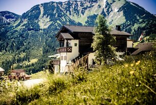 Haus vor Bergkulisse mit Wiesen im Vordergrund