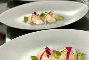 Drei Teller mit angerichteten Fischscheiben, Avocado und Radieschen
