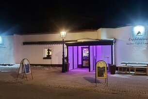 Gebäude mit lila beleuchtetem Eingangsbereich bei Nacht