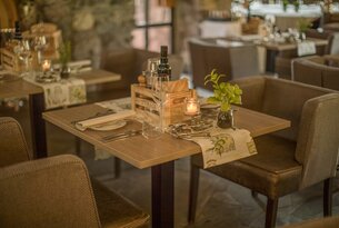Gedeckter Tisch mit Holzkiste, Flasche, Gläsern, Brot, Kerze und Pflanze in einem Restaurant