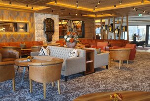 Lobby mit Sofas, Sesseln, Dekoration und Holzdecke in warmen Farben