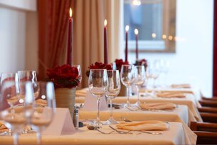 Festlich gedeckter Tisch mit Kerzen, Blumen und Weingläsern