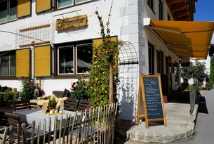Restaurantfassade mit gelben Fensterläden, Speisekarte und Außenterrasse
