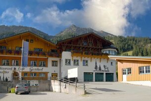 Gasthof mit Hirsch-Motiv vor Bergkulisse