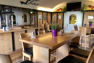 Innenansicht eines Restaurants mit Holztischen und Stühlen
