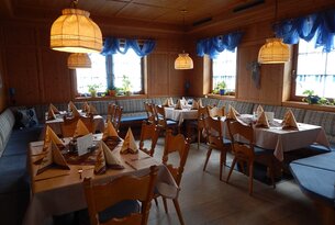 Gemütliches Restaurant mit Holzwänden, gedeckten Tischen und blauen Vorhängen