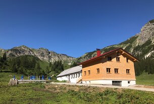 Hütte vor Berglandschaft unter blauem Himmel