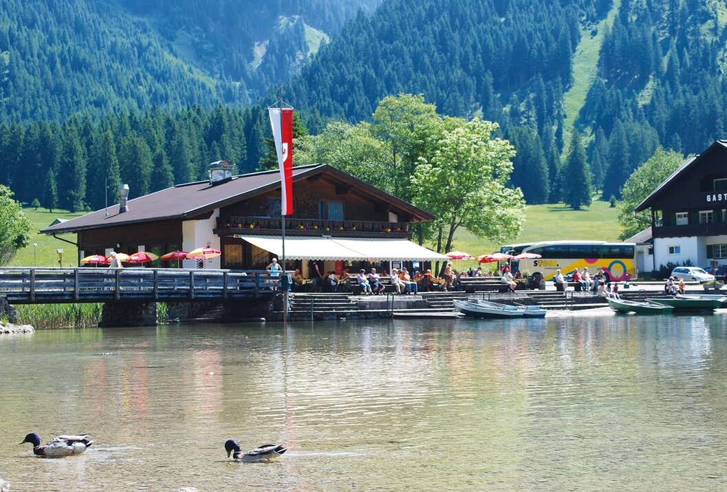Restaurant am See mit österreichischer Flagge vor Bergkulisse