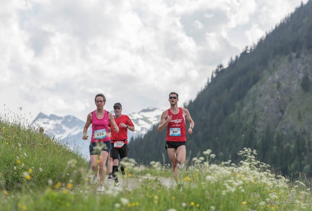 Drei Läufer beim Berglauf vor Bergkulisse