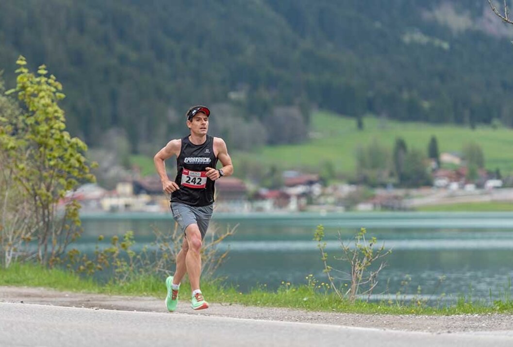 Läufer mit Startnummer 242 beim Marathon vor Bergkulisse
