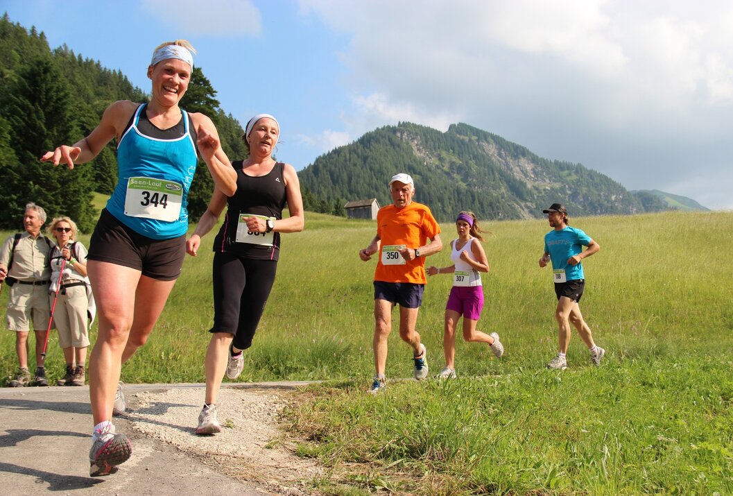 Gruppe von Läufern bei einem Wettlauf in ländlicher Umgebung mit Bergen im Hintergrund