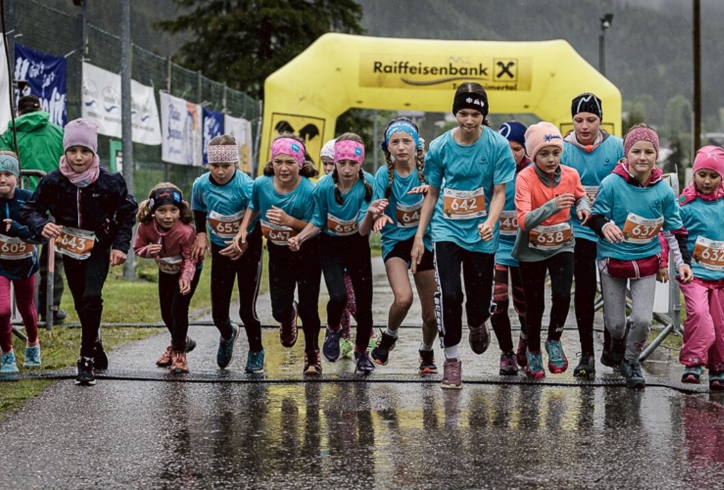 Gruppe junger Mädchen startet bei einem Lauf vor gelbem Raiffeisenbank-Bogen