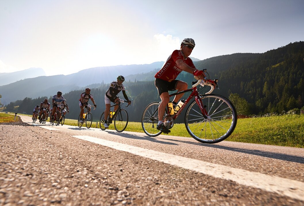 Radfahrer-Gruppe fährt auf einer Straße vor grüner Landschaft