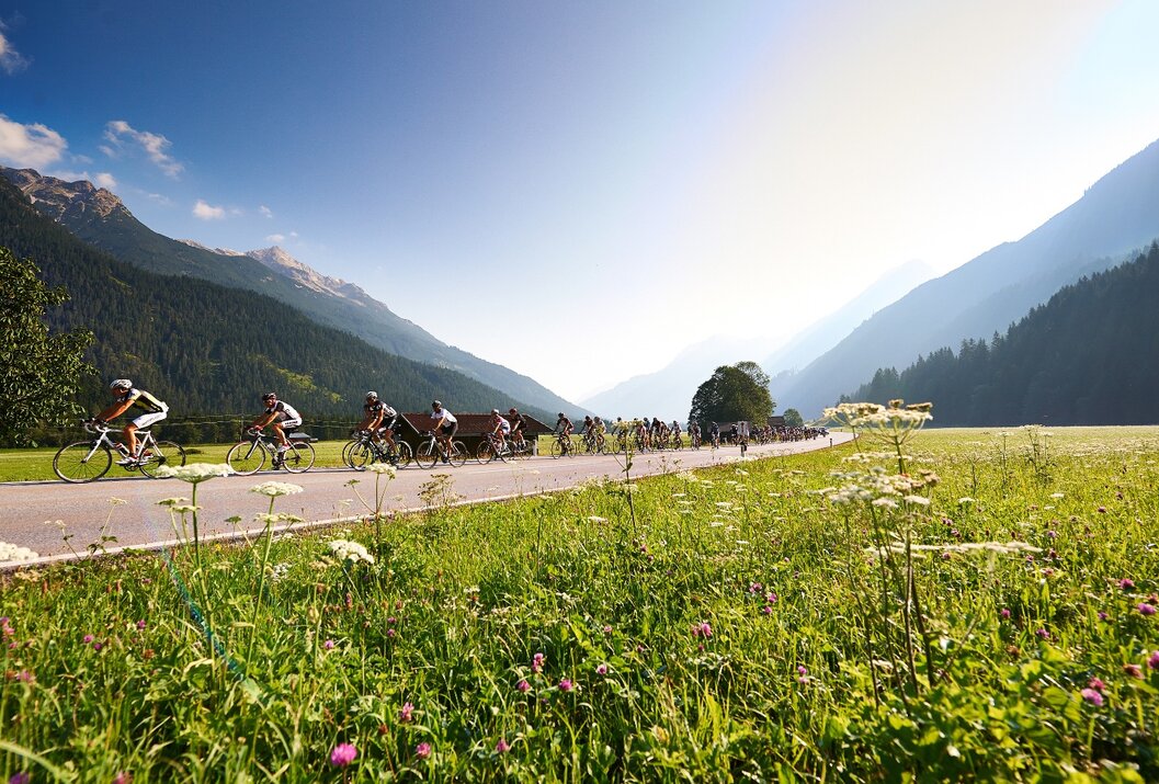 Radfahrer auf Straße in grüner Landschaft mit Bergen im Hintergrund