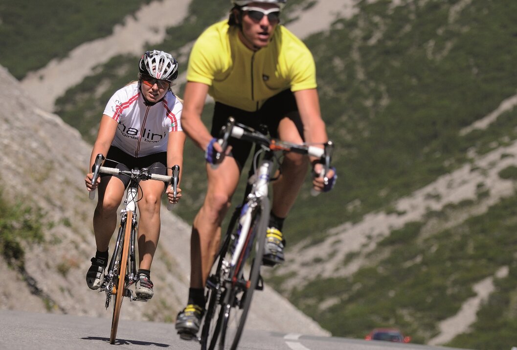 Zwei Radfahrer fahren bergauf, tragen Helme und Sportkleidung