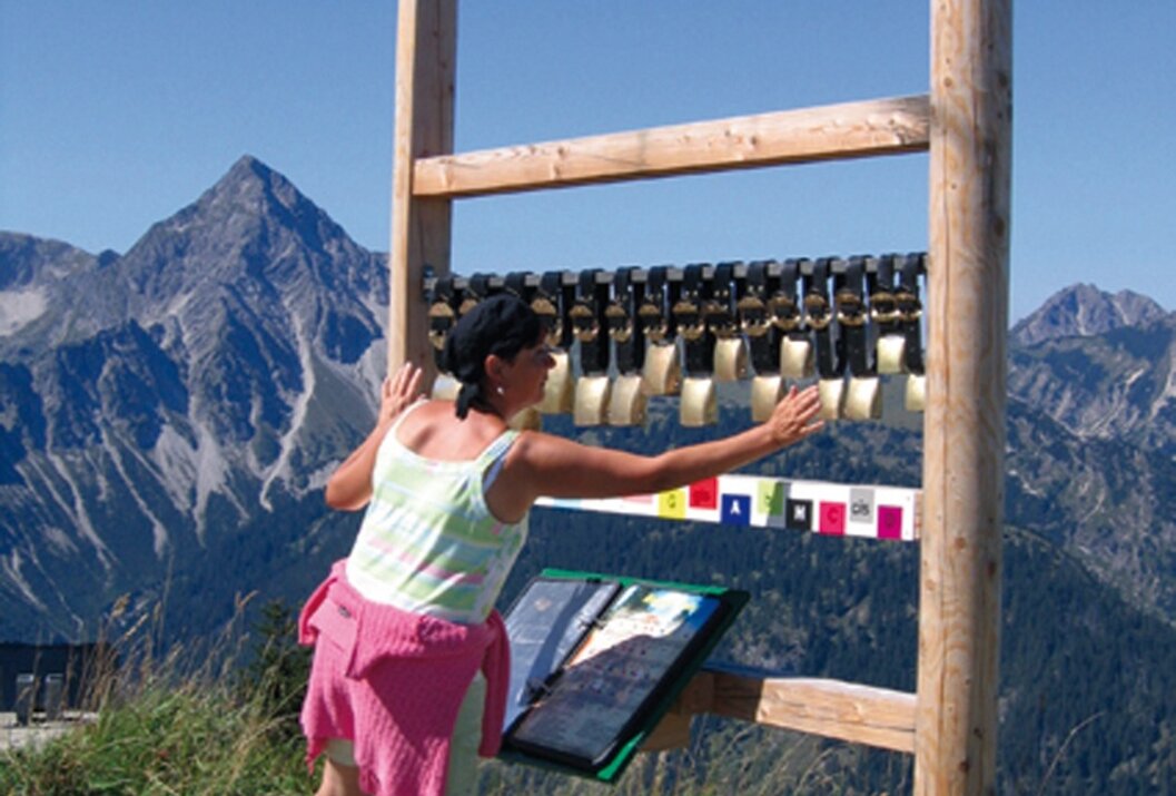 Frau spielt Glockenspiel vor Bergpanorama