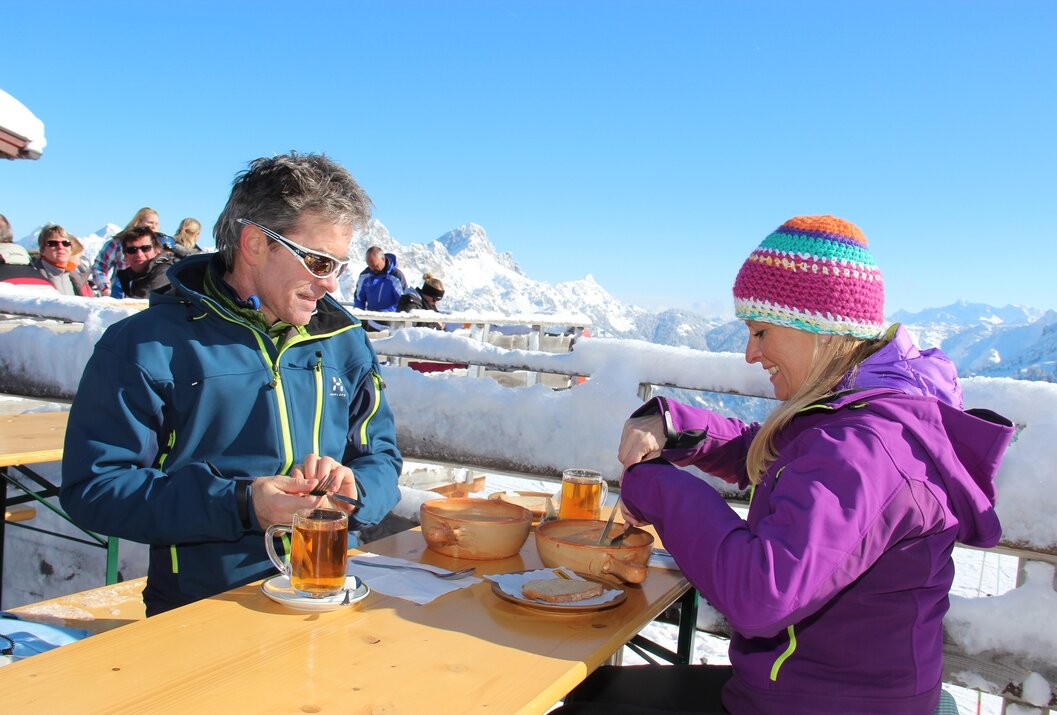 Paar isst Suppe auf einer Sonnenterrasse in den Bergen