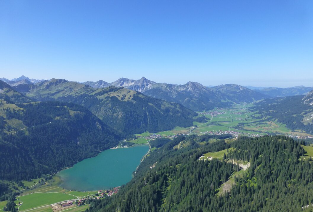 Luftaufnahme von See, Bergen, Tal und Wald unter blauem Himmel