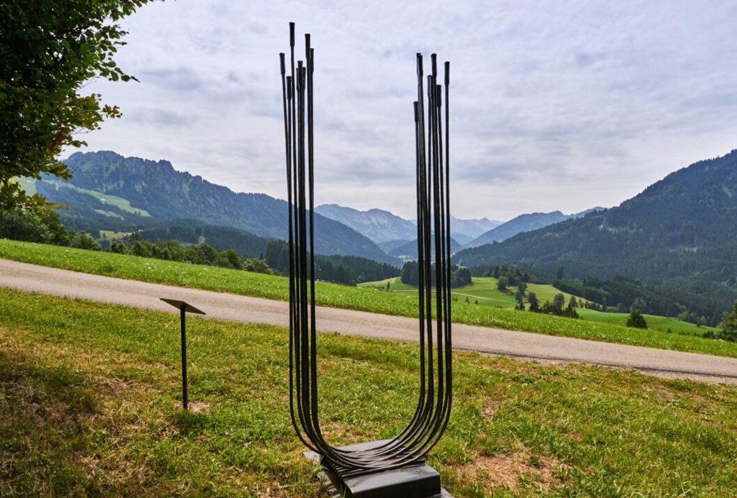 Skulptur aus Metallstäben in U-Form vor Berglandschaft