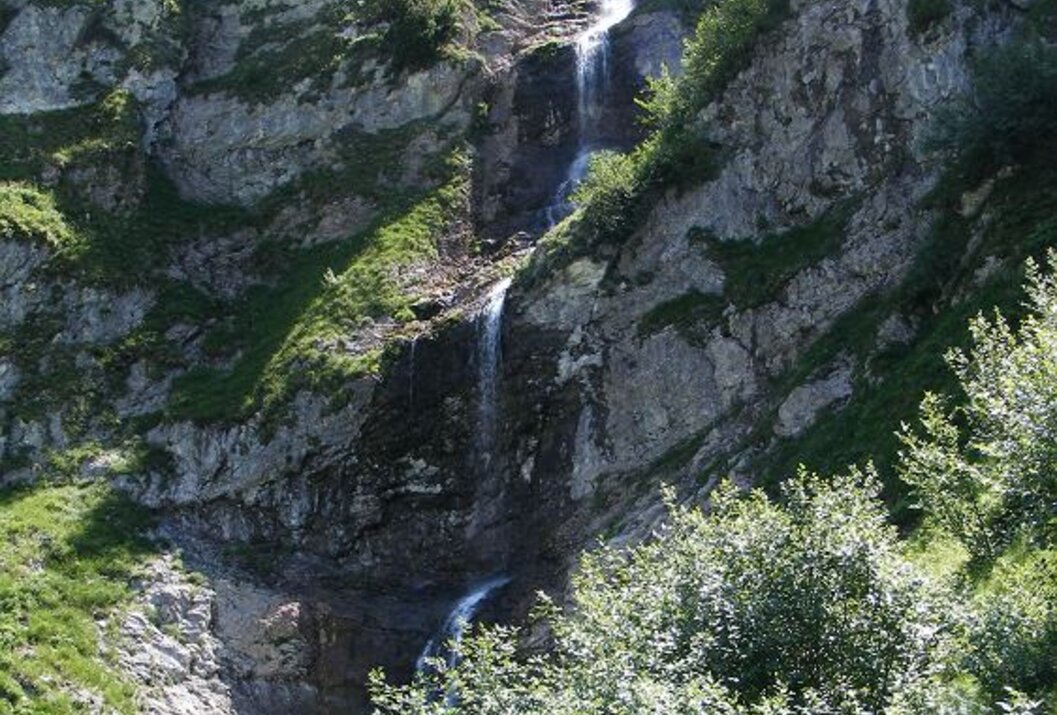 Wasserfall stürzt über felsige Klippe mit grüner Vegetation