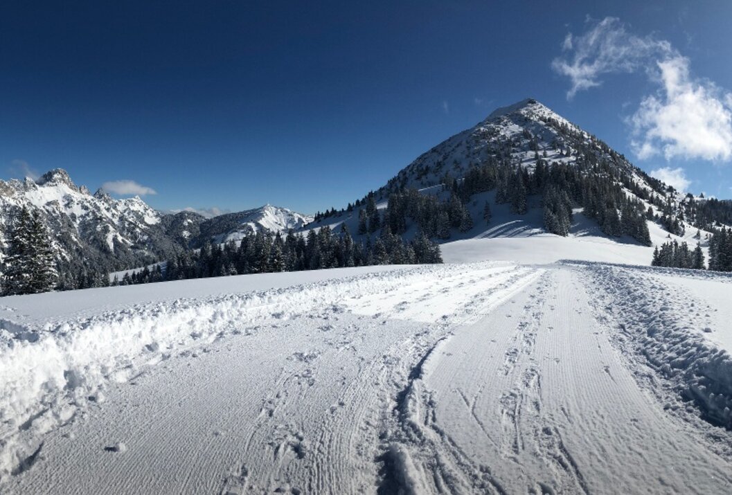 Verschneite Berglandschaft mit blauem Himmel und einzelnen Wolken