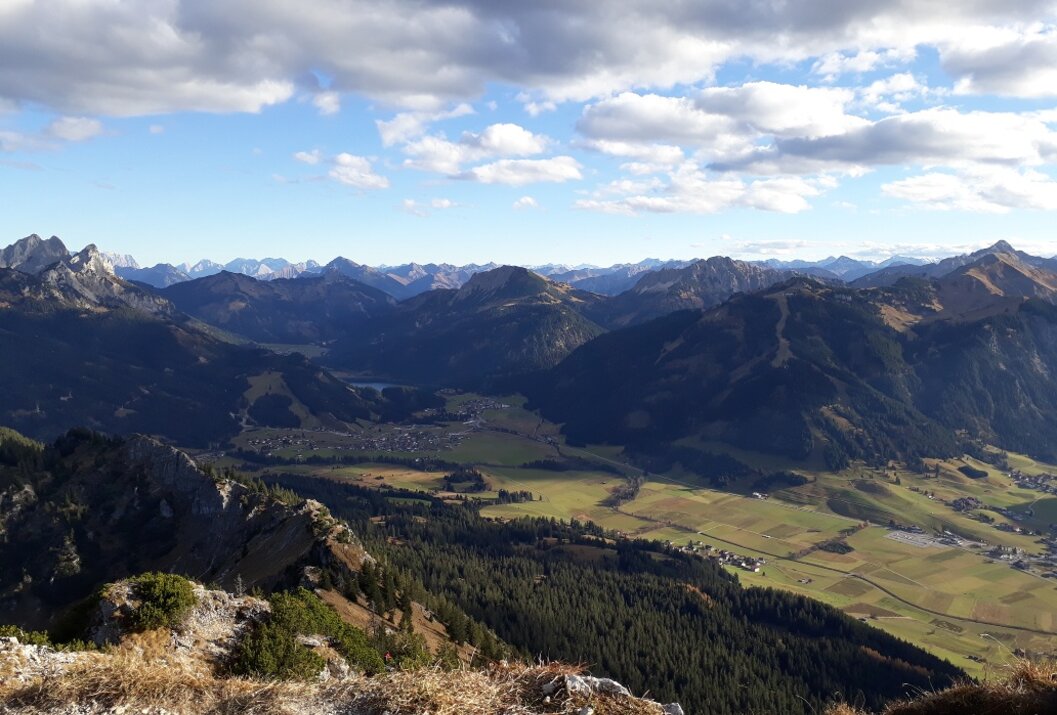 Berglandschaft mit Tal, Wäldern und blauem Himmel mit Wolken