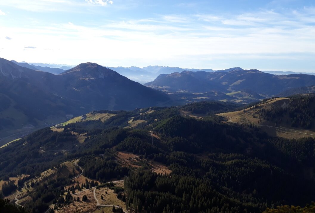 Berglandschaft mit bewaldeten Hügeln unter blauem Himmel