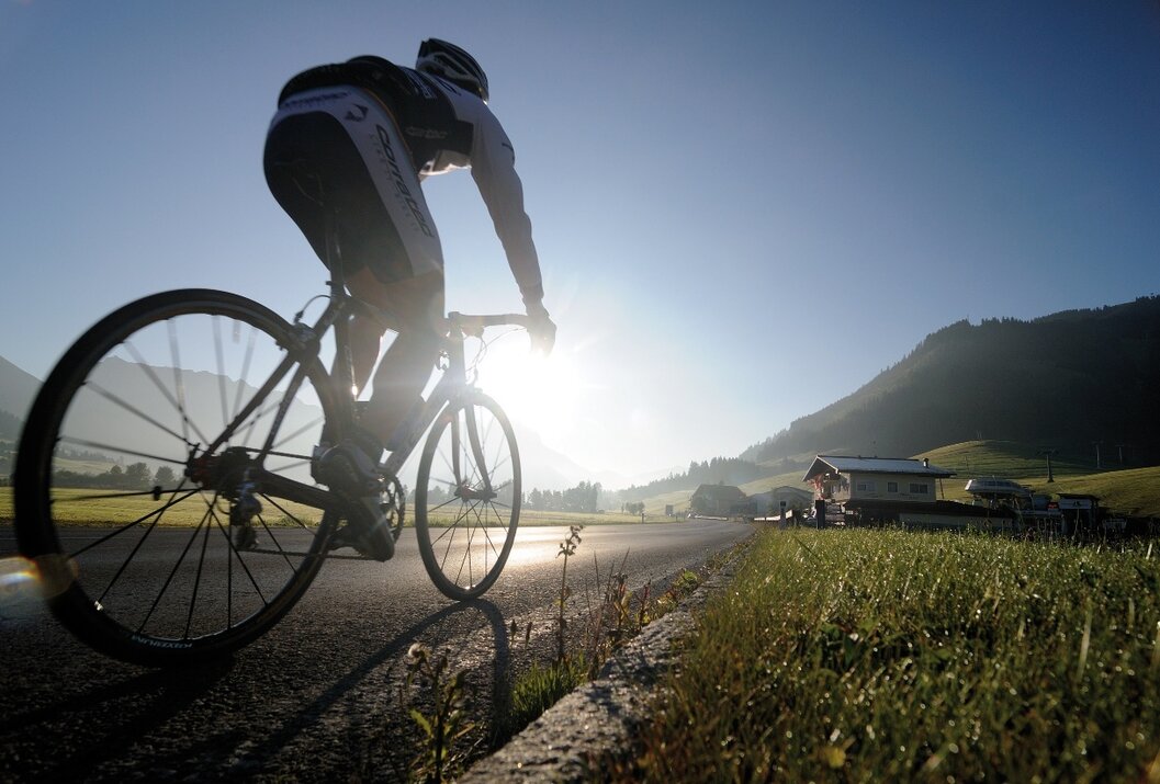 Radfahrer fährt auf Landstraße mit Bergen im Hintergrund