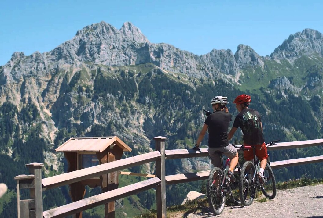 Zwei Mountainbiker mit Blick auf Berglandschaft an einem sonnigen Tag