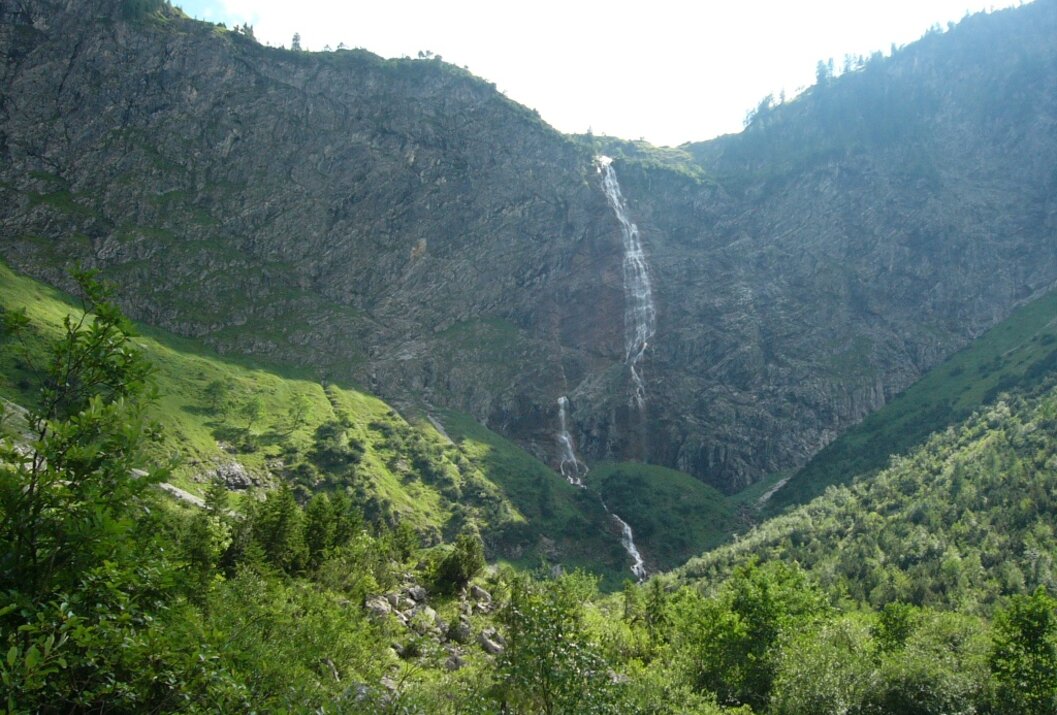 Wasserfall an einem steilen Berghang mit grüner Vegetation