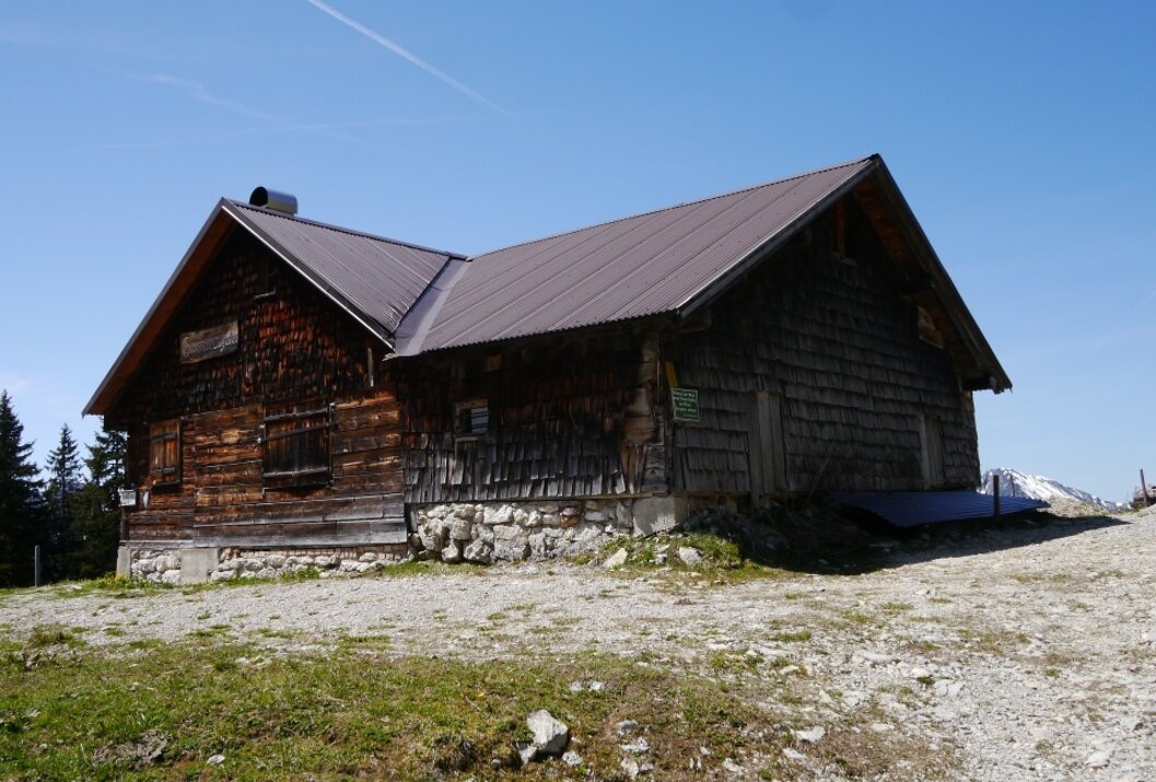 Holzhütte mit braunem Dach vor blauem Himmel