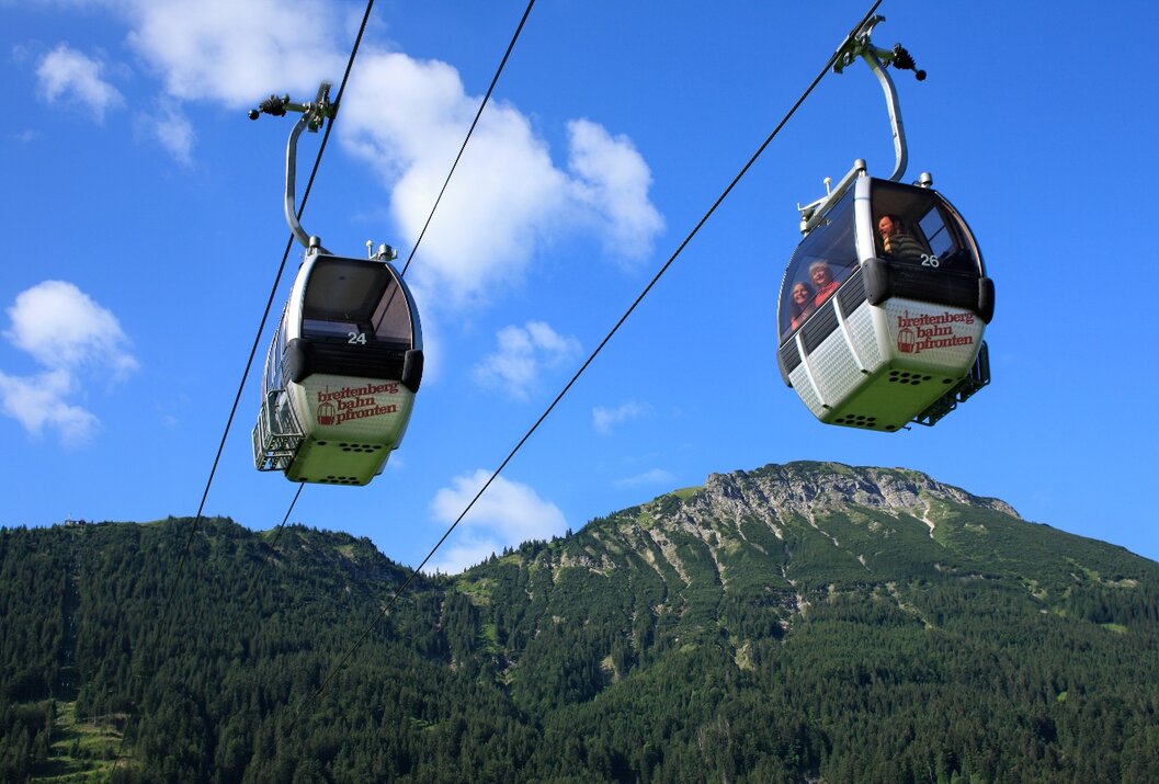 Zwei Gondeln einer Seilbahn vor Berglandschaft und blauem Himmel