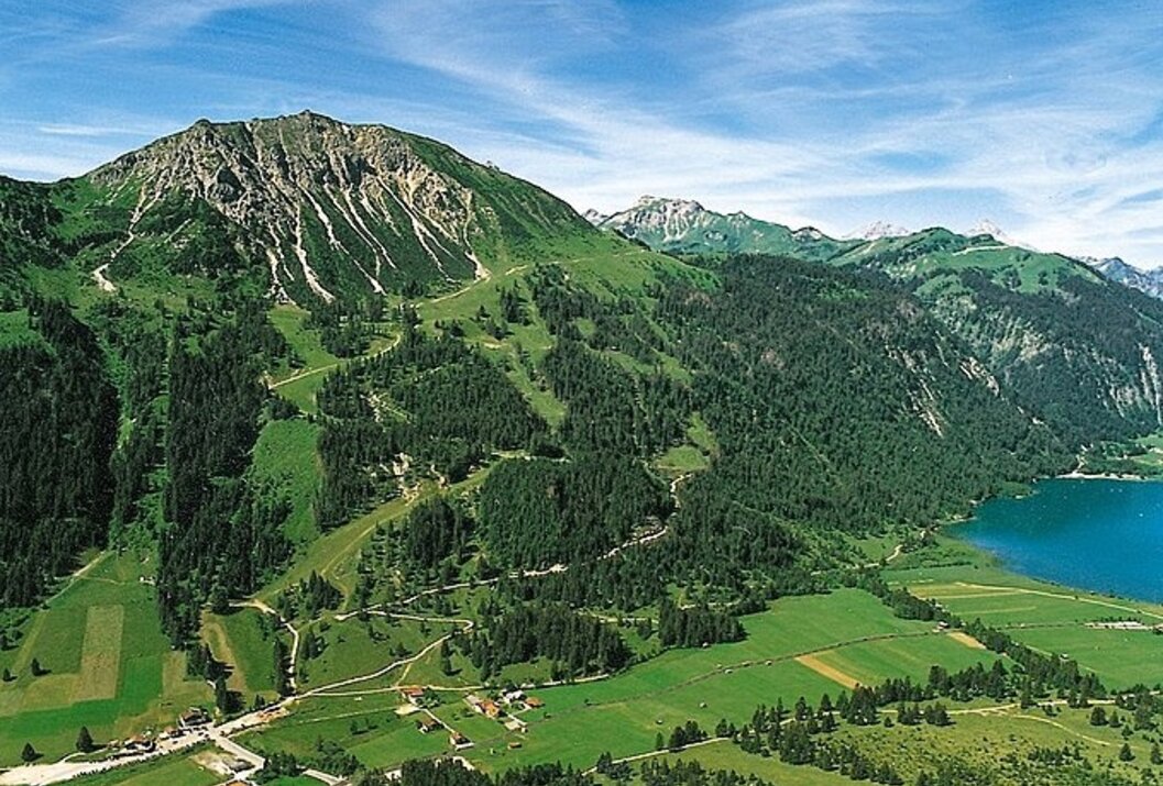 Grüne Hügel und Berge unter blauem Himmel mit vereinzelten Wolken