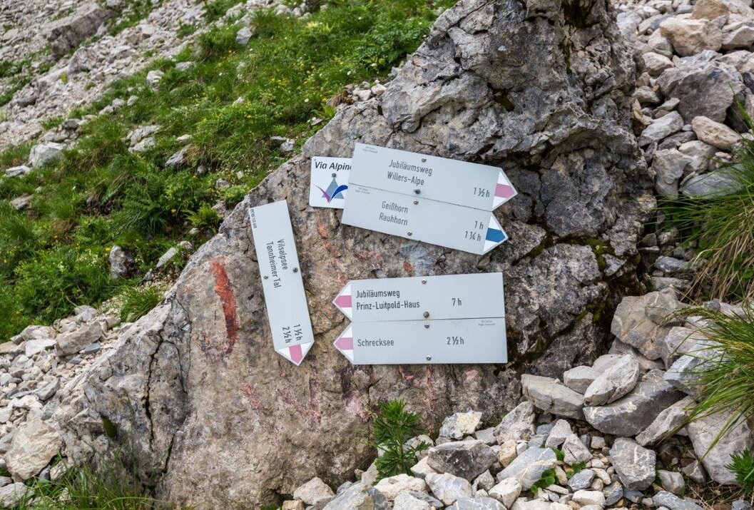 Wegweiser an Felsen in den Bergen mit Zielen wie Jubiläumsweg und Schrecksee