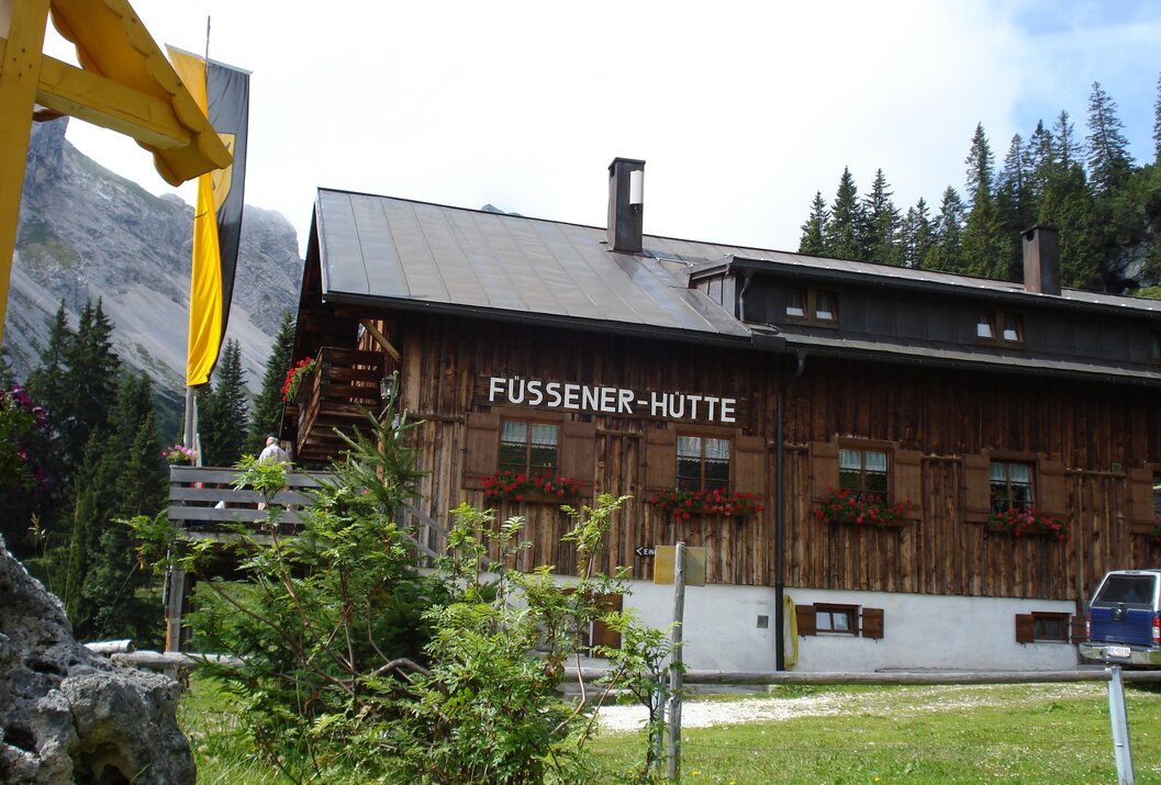 Hölzerne Füssener Hütte mit Blumenkästen vor Bergkulisse