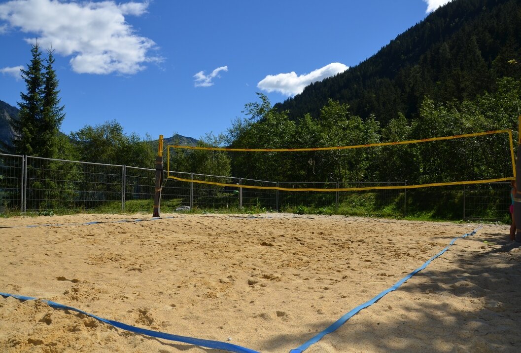Sandvolleyballfeld vor Berglandschaft unter blauem Himmel