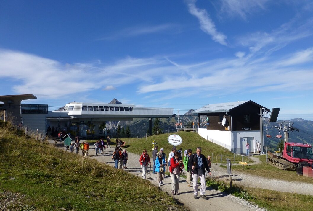 Wandergruppe auf Bergpfad mit Seilbahnstation im Hintergrund