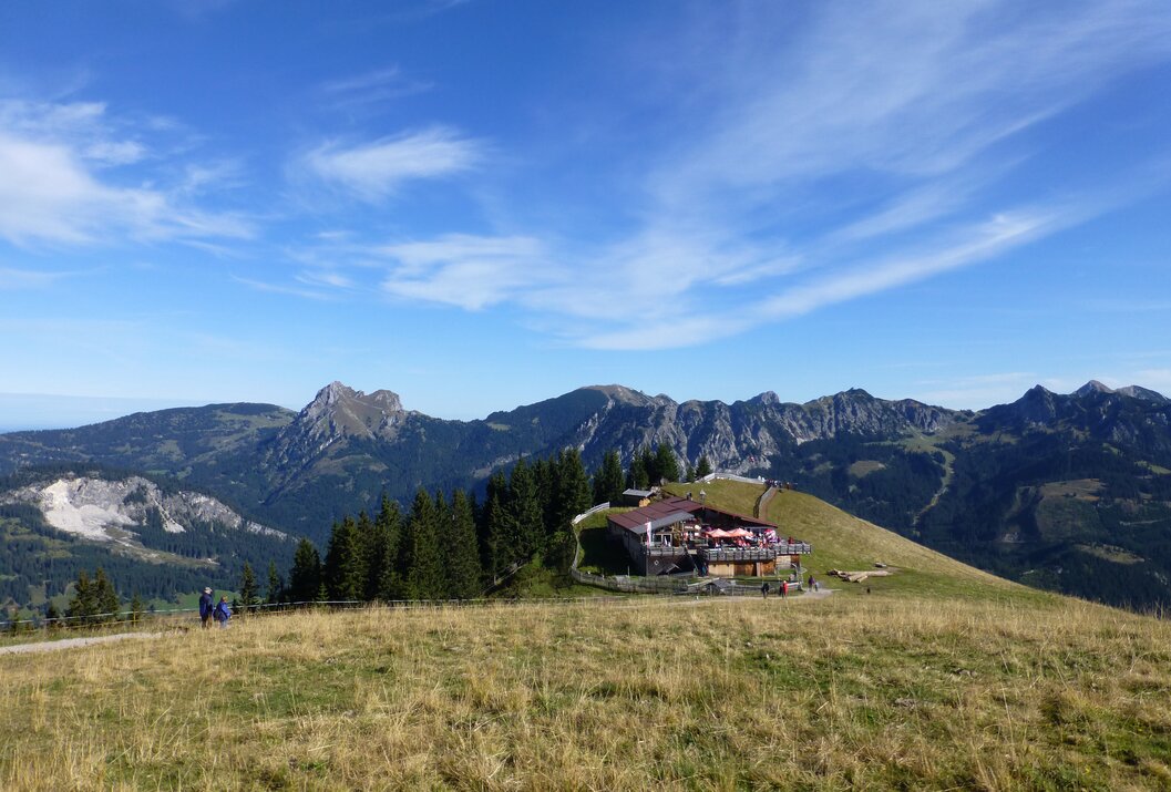 Berglandschaft mit Hütte auf Wiese unter blauem Himmel