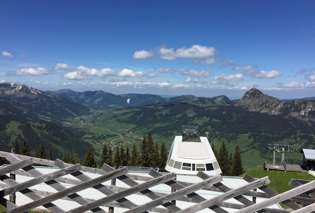 Berglandschaft mit Seilbahnstation im Vordergrund unter blauem Himmel