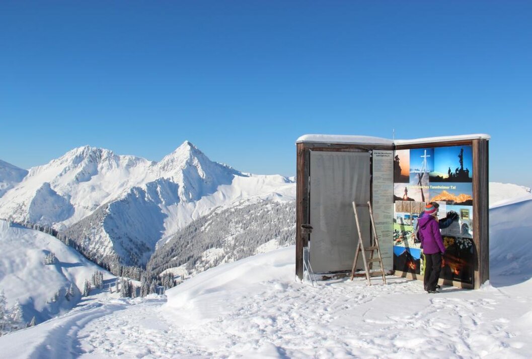 Schneebedeckte Berge und blauer Himmel hinter einem kleinen Verkaufsstand auf einem Gipfel