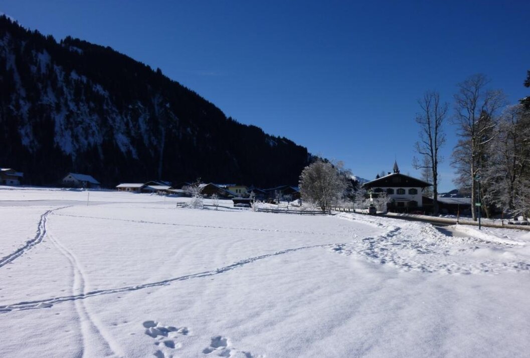 Winterlandschaft mit Schnee, Bergen, Häusern und blauem Himmel