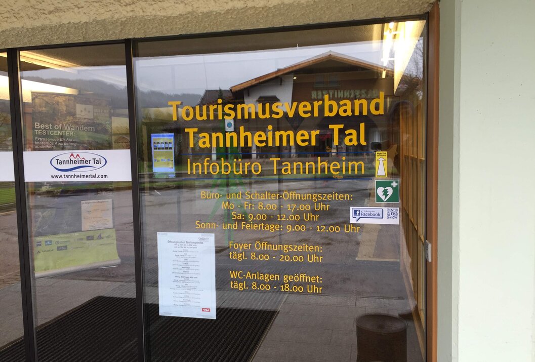 Eingang zum Tourismusverband Tannheimer Tal mit Öffnungszeiten auf der Glastür